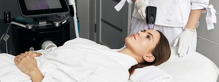A relaxed patient receives Morpheus8 microneedling with radiofrequency treatment on her forehead.